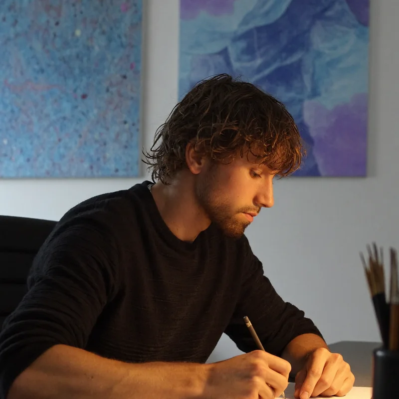 Mathew Groen aan zijn werktafel, tekenend met potlood op papier.